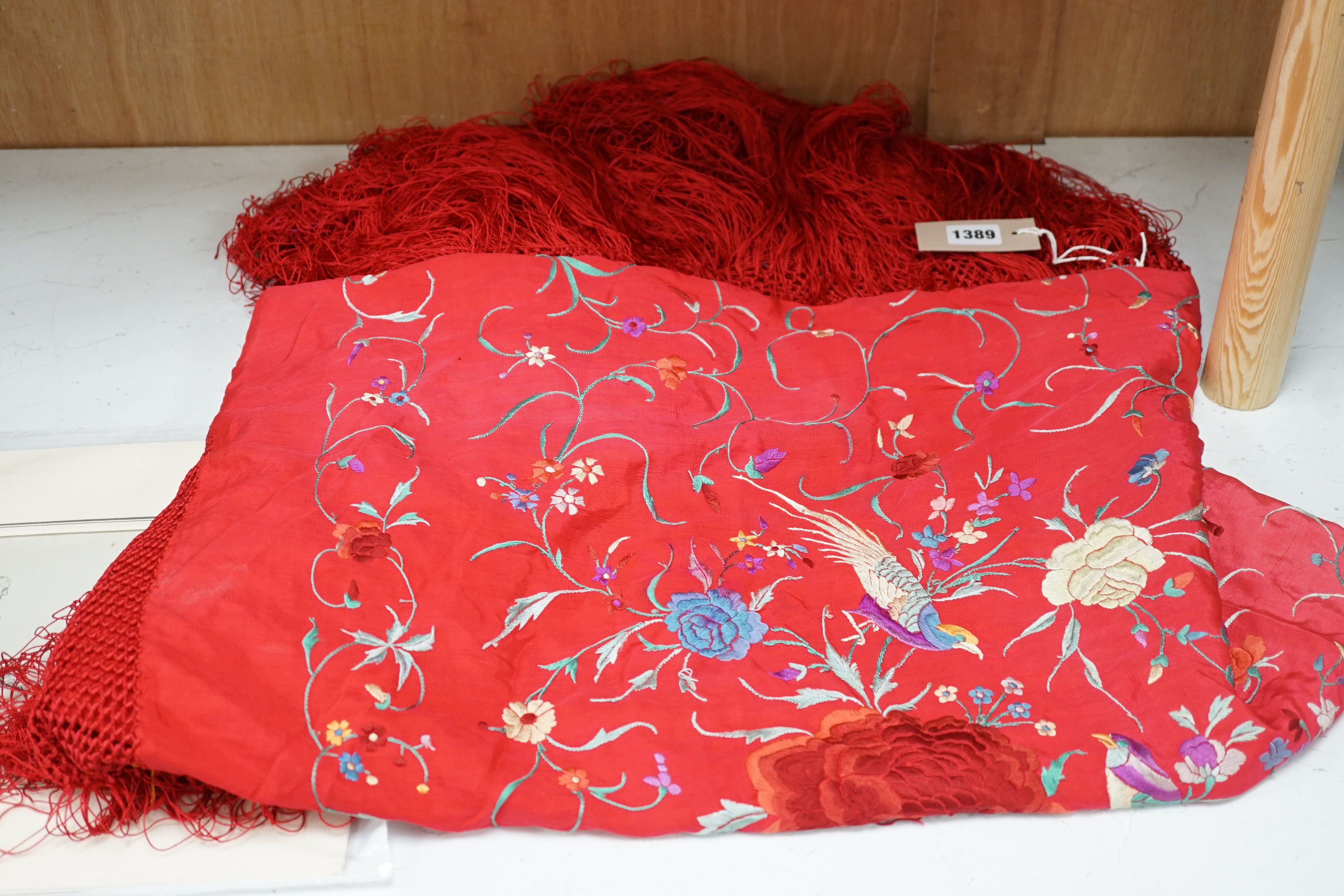 An early 20th century Chinese red silk fringed shawl, with multicoloured polychrome embroidery, 130cms square not including fringe